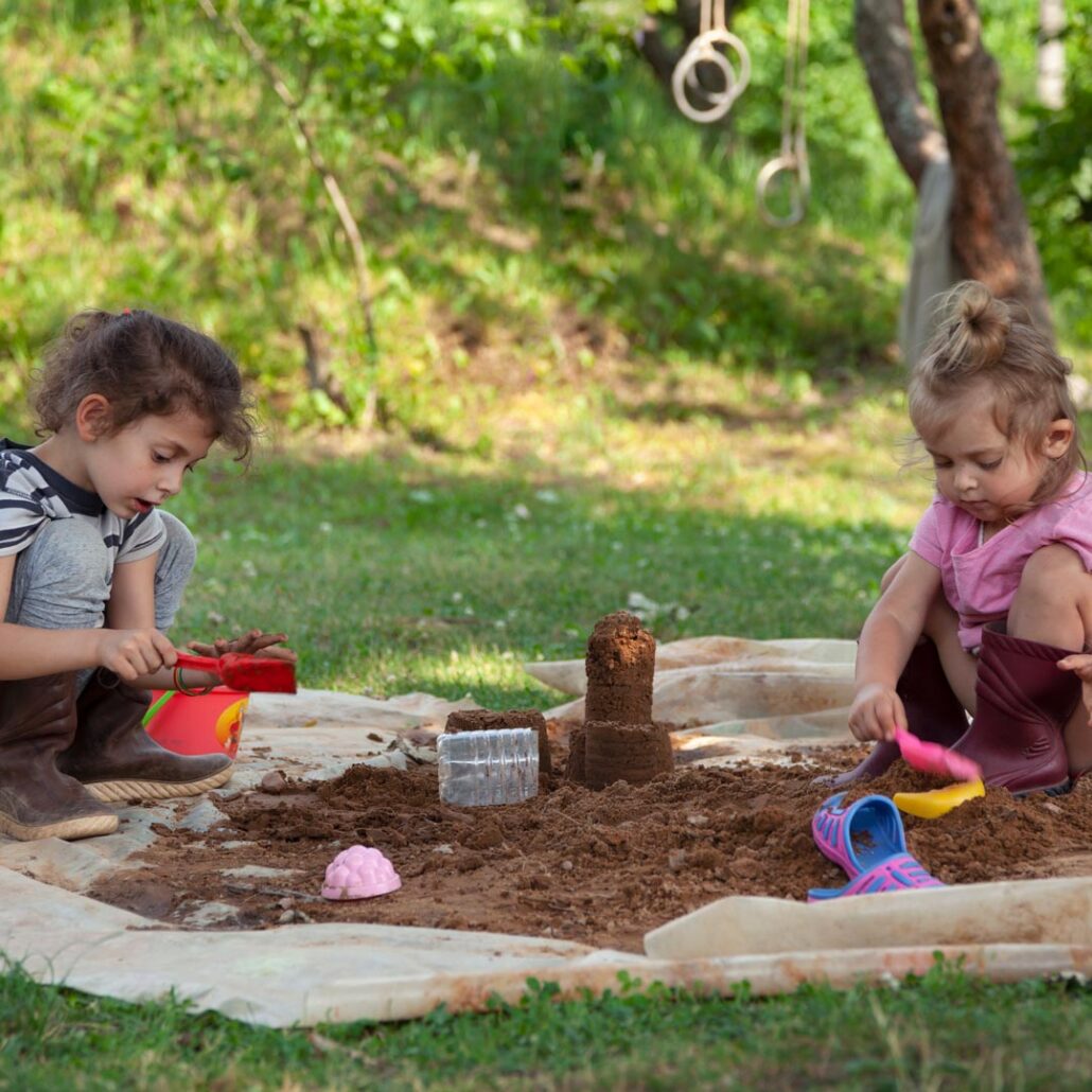 Sand im Garten: Zwei Kinder spielen im Sandkasten